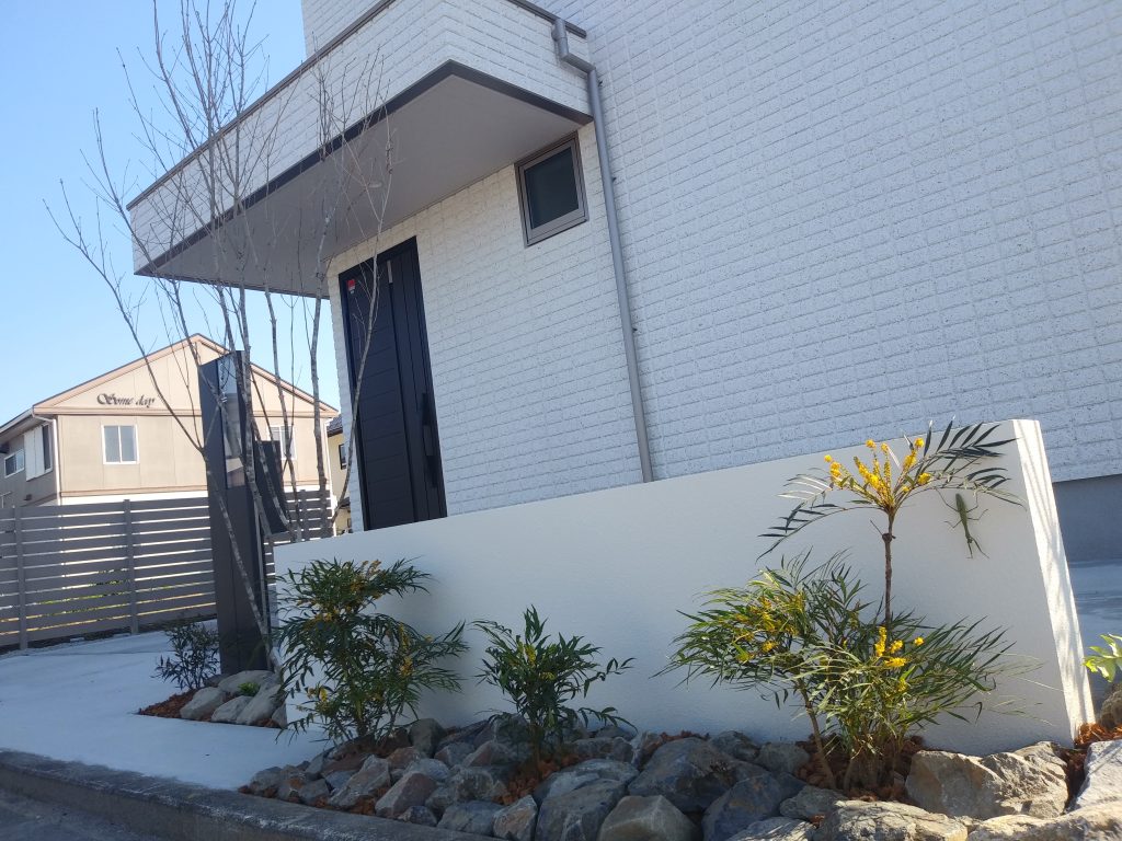 壁の前には常緑性のホソバヒイラギを植栽。